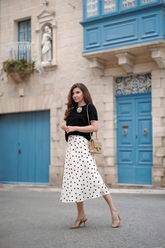 a lady wears a polka dot printed midi skirt with a black top